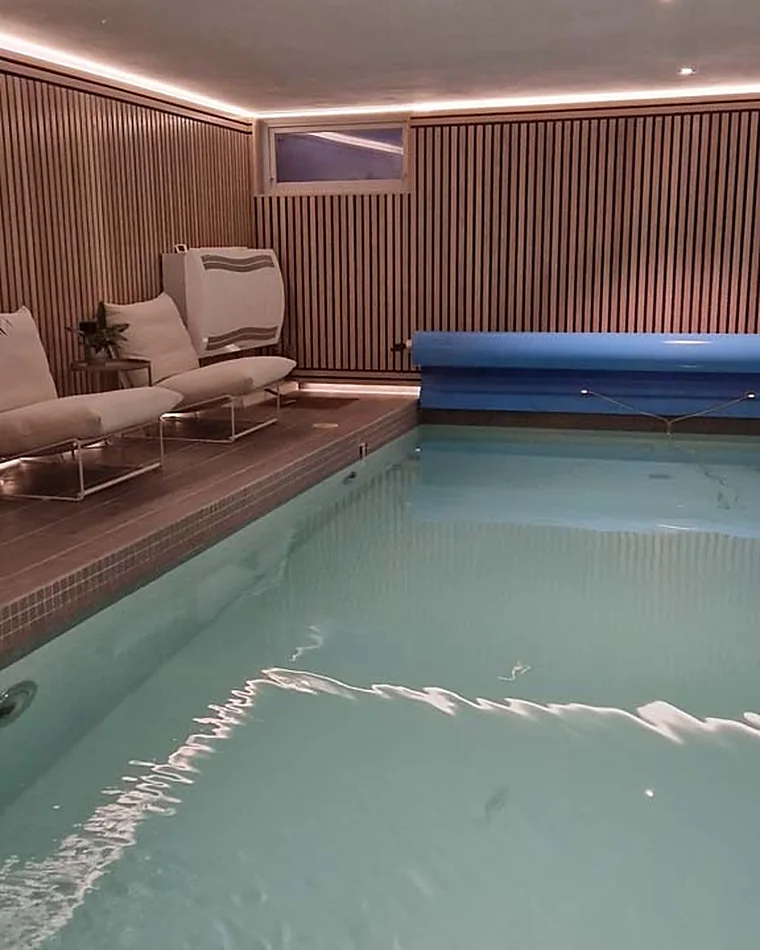 Innendørs svømmebasseng med liggestoler langs kanten